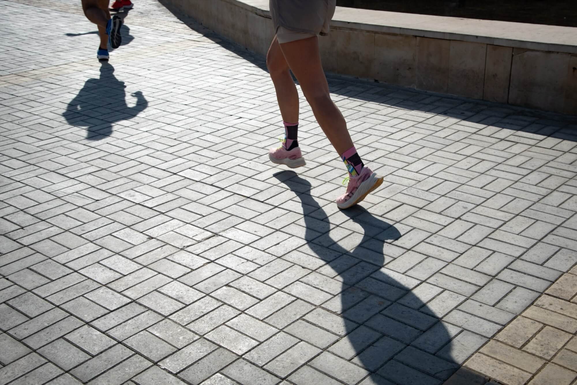 Kaksi ihmistä juoksee vastalevytetyllä betonikävelytiellä, joka on päällystetty koristeellisella kuvioinnilla.